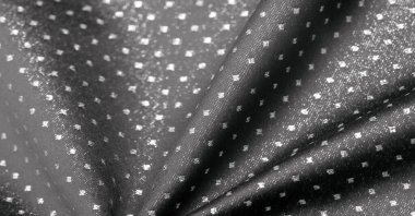 Küçük polka şeklinde metalik bir parıltıya sahip kumaş, siyah, soyut bir polikrom desen, uzay çağı estetiğine sahip siyah bir arkaplan karşısında parıldıyor ve bu kumaşa fütüristik bir gelecek hissi veriyor.