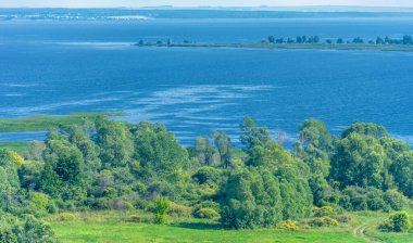Yaz manzarası. Dünyanın Avrupa bölgesindeki bir nehir. Güneşli sıcak bir gün. Yeşil ağaçlar, çimenler. Mavi gökyüzü küçük bir bulut örtüsüyle.