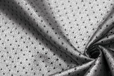 Küçük polka şeklinde metalik bir parıltıya sahip kumaş, siyah, soyut bir polikrom desen, uzay çağı estetiğine sahip siyah bir arkaplan karşısında parıldıyor ve bu kumaşa fütüristik bir gelecek hissi veriyor.