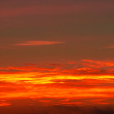 Bulutlu, güneşli, gün batımlı, batan güneşin turuncu-sarı tonlarıyla gökyüzünün fotoğrafı.