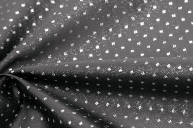 Küçük polka şeklinde metalik bir parıltıya sahip kumaş, siyah, soyut bir polikrom desen, uzay çağı estetiğine sahip siyah bir arkaplan karşısında parıldıyor ve bu kumaşa fütüristik bir gelecek hissi veriyor.