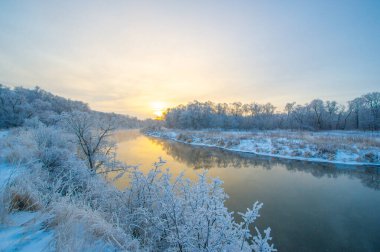 Doğanın nefes kesen manzarasına tanık olun. Güneş, gökyüzünü turuncu ve pembe tonlarıyla renklendiriyor. Sıcak parıltısını buz nehrine saçıyor. Kış Sihirli Doğa Mükemmelliği