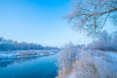 Doğanın kış büyüsünün çarpıcı güzelliğini tecrübe edin. Güneşin turuncu ve pembenin canlı tonlarına dönüşünü izleyin. Ilık parıltı buzlu nehri yansıtırken büyüyü yakala.