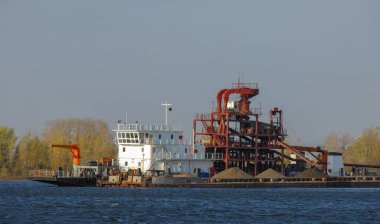 Sonbahar manzarası, nehir, nehirde yapılan çalışmalar, nehir botları, güneşli bir gün, rüzgar dalgaları yükseltiyor, suyun koyu kurşun rengi.,