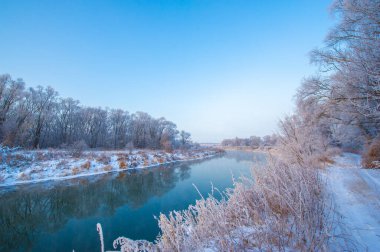 Tüm ihtişamıyla doğanın güzelliğinin tadını çıkar. Güneşin gökyüzünde çarpıcı bir tuval çizişini izleyin. Arka planda buzlu bir nehirle mükemmel bir kış anını yakala..