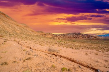 Kızıl Boguta Dağları 'nda çölün batışının büyüleyici güzelliğinin tadını çıkar. Pürüzlü tepelerin ardında batarken güneşin altın parıltısına tanık olun. Nefes kesen manzaraya hazır olun.