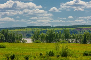 Yaz manzarası, nehir taşkınları, pitoresk kıyılar, kır çiçekli parlak yeşil çimenler, beyaz bulutlu mavi gökyüzü, ılık yaz günleri.,