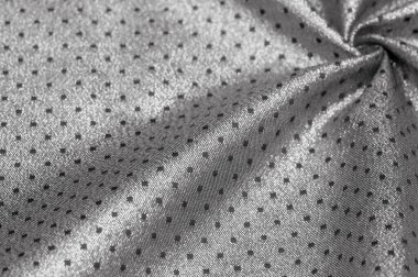 Küçük polka şeklinde metalik bir parıltıya sahip kumaş, siyah, soyut bir polikrom desen, uzay çağı estetiğine sahip siyah bir arkaplan karşısında parıldıyor ve bu kumaşa fütüristik bir gelecek hissi veriyor.