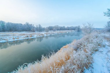 Garip bir kış harikalar diyarının güzelliğini tecrübe et. Donmuş nehrin üzerinden altın güneşin doğuşunu izle. Kış harikalar diyarının büyüsünü tecrübe et. Buz gibi şafak.