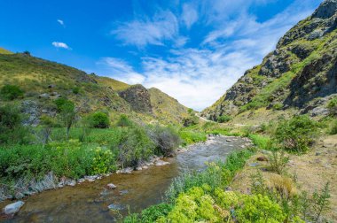 Dağ nehri kanyonunun huzurlu güzelliği. Nehir boyunca görkemli manzaraları ve şelaleleri keşfedin. Bu doğal harikalar diyarında yürüyüş, balık tutma ve kamp gibi doğa aktivitelerinin tadını çıkarın..