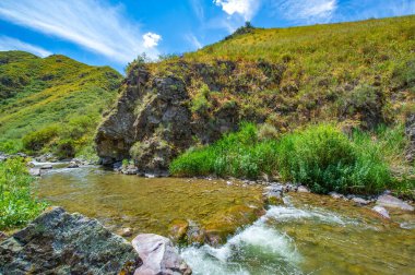 Kayalık kanyonda akan nehrin doğal güzelliğini hissedin. Kendini dağların sakin atmosferine daldır. Bu resmedilmeye değer manzarada gizli doğa harikalarını keşfedin..