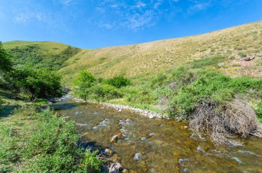 Kayalık bir dağ kanyonundaki doğanın çarpıcı güzelliğinin tadını çıkar. Nehrin dağların kalbinden zarifçe akışını izle. Nefes kesici manzaranın tadını çıkarın ve doğal dünyayla yeniden bağlantı kurun..