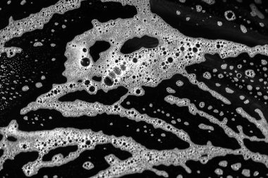 Siyah bir tabakta sabun köpüğünün eşsiz ve yaratıcı görüntüsü. Beyaz köpük ve koyu arkaplan arasındaki zıtlık çarpıcı bir görsel etki yaratır. Temizlik ve hijyen göstergesi