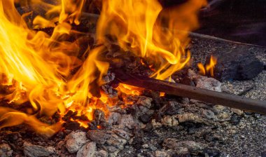 Old-fashioned blacksmith furnace with burning coals. Embers and Flame of a smith's forge. Heated bugle with red coals.  clipart