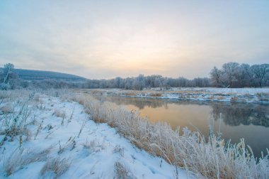 Kış Harikalar Diyarı huzurlu ve huzurlu bir yerdir. Güneş donmuş nehirde güzel bir altın ışık yaratıyor. Doğanın güzelliği bu resim sahnesinde sergileniyor..
