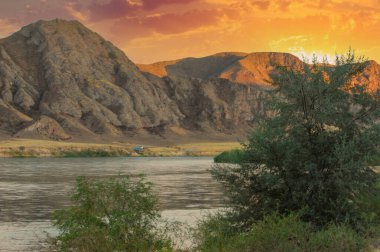 Doğanın dingin güzelliğinin tadını çıkar. Nehrin arazide nasıl huzur içinde aktığına bakın. Güneşin altındaki dağların ve ağaçların nefes kesici manzarasının tadını çıkar..