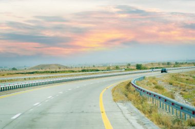 Uzağa uzanan beton bir yolu olan güzel bir çayır manzarası. Gün batımının çarpıcı renkleri gökyüzünü aydınlatıyor. Huzurlu ve huzurlu sahne, 10. 07 numara. 2020 yılı. Kazakistan Almatı