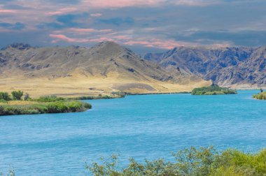 Sakin nehrin üzerinde günbatımının huzurlu güzelliğinin tadını çıkar. Kendinizi görkemli dağlara ve yemyeşil ağaçlara daldırın. Doğanın huzur ve sükunetini tecrübe et..