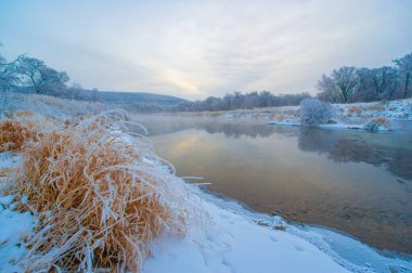 Donmuş nehir güneşin sıcak altın ışığını yansıtır. Sahne huzur ve sükuneti çağrıştırıyor. Doğanın güzelliği bu kış harikalar diyarında belli. Güneş ufuktan yükseliyor.