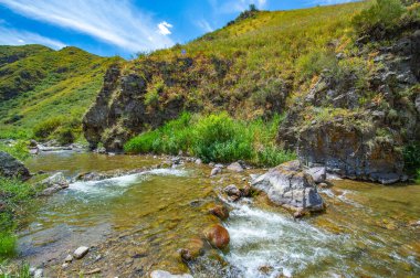 Görkemli nehir kayalık kanyonda zarafetle akıyor. Doğanın güzelliği dağların tam kalbinde ortaya çıkar. Akan suyun ve engebeli arazinin huzurlu sakinliğini hisset..