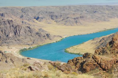 Nehrin güzelliğinin ve huzurunun tadını çıkar. Berrak mavi suyun ve ayaklarının altındaki kayaların tadını çıkar. Arkanıza yaslanın ve akan nehrin rahatlatıcı seslerine kulak verin..