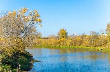 Nehir kenarındaki değişen mevsimlerin güzelliğini hissedin. Yüzeydeki sonbahar yapraklarının yansımaları. Sığ nehir, akışı yumuşak bir akıntıya yavaşlarken gizli kayaları ve kumsalları ortaya çıkarır.