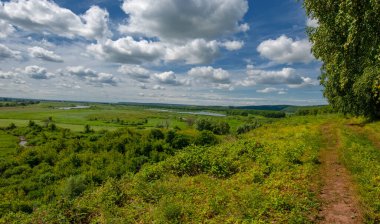 Yaz, tepe, tepeler, huş ağaçları dağların yamaçlarında büyürler. Yamaç boyunca dönen toprak bir yol, sıcak yaz günleri.