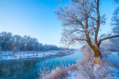 Tüm ihtişamıyla doğanın güzelliğinin tadını çıkar. Güneşin gökyüzünde çarpıcı bir tuval çizişini izleyin. Arka planda buzlu bir nehirle mükemmel bir kış anını yakala..