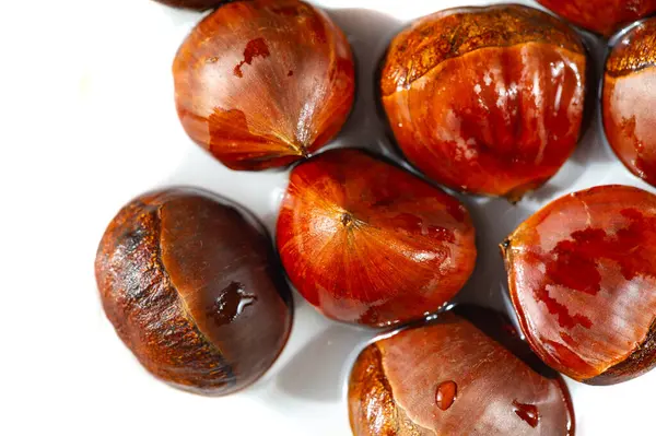 Beyaz arka planda kestane renginde narin kestaneler. İyiliğin sembolü olarak yaratıcı bir şekilde şekillendirilmiş. Kıtır beyaz arka plana sezonluk cazibe yayıyor. Doğa Sanatı