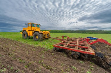 Bahar fotoğrafçılığı, ziraat makineleriyle manzara, bir traktör tarlayı sürüyor, tarlayı sürüyor, kuşlar ekilebilir arazinin üzerinde uçuyor.