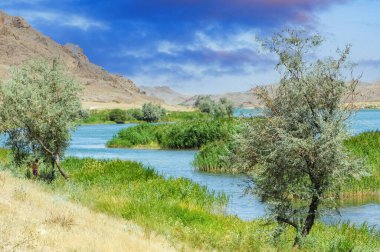 Muhteşem dağların arasından akan nehrin nefes kesici manzarası sakin nehir manzarasının üzerindeki günbatımını izleyin. Etrafınızı saran yüksek uçurumlar ve gür ağaçlarla doğanın güzelliğini keşfedin.