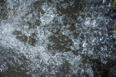 Suda hava kabarcıkları olan bir dağ nehrinin bulanık ve çarpıcı manzarası. Saf sıvı hazzın büyüleyici dansını deneyin. Kendini doğanın nirvanasına su fısıltılarıyla daldır..