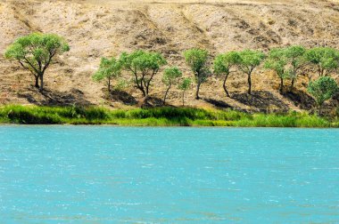 Güneş, doğal cennet ufkunun üzerinde batarken yükselen dağlar ve yemyeşil ağaçlarla çevrili kayaların arasında zarifçe dolaşan nehrin çarpıcı güzelliğine bakın.