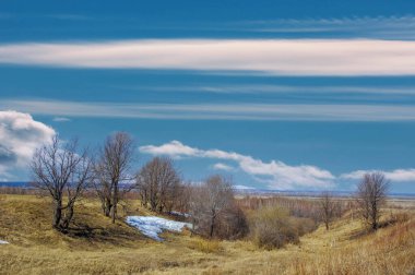 Sarı tarlalar ve seyrek otlar baharın başlangıcını işaret ediyor. Ağaçlar çıplak, yapraklar yok. Yeni bir büyüme için hazırlanıyorum. Erimeden önce yere yapışan karın son kalıntıları..