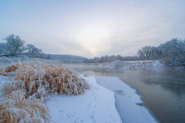 Nefes kesici manzaralı bir kış cenneti. Güneşin doğuşu büyülü bir atmosfer yaratır. Huzurlu ve huzurlu bir atmosfer. Donmuş nehir güzelliği artırır. Doğa en güzel haliyle.