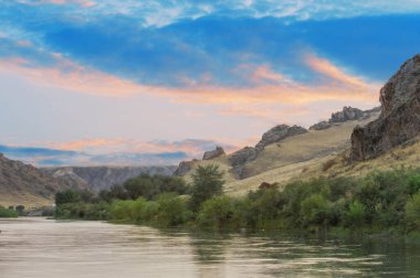 Çarpıcı uçurumların ve dolambaçlı çayır nehrinin tadını çıkar. Vahşi doğada gün batımının dramatik renklerine tanık olun. Bozulmamış doğal manzaraların vahşi güzelliğine dalın..
