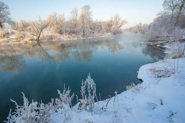 Kış gündoğumunun nefes kesici güzelliğinin tadını çıkar. Doğanın sıcak ve serin renklerinin mükemmel bir kombinasyonuna tanık olun. Güneşin buzlu nehre yansıyan çarpıcı fotoğraflarını çek..