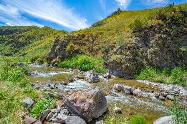Kayalık kanyonda akan nehrin doğal güzelliğini hissedin. Kendini dağların sakin atmosferine daldır. Bu resmedilmeye değer manzarada gizli doğa harikalarını keşfedin..