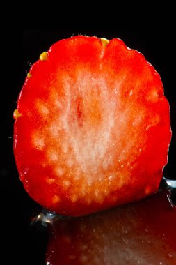 Sağlığınızı sulu ve lezzetli kılmak için vitaminlerle dolu siyah bir zemin üzerinde canlı çilek tasarımı. Tariflere abur cubur eklemek için ideal.