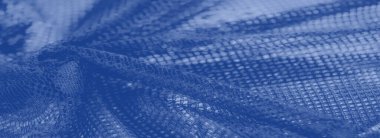 Bulanık, dekoratif ağ dokusuna sahip yumuşak mavi kumaşın detaylı bir görüntüsü, karmaşık desenleri ortaya çıkarıyor ve yüzeyindeki ışık ve gölgenin ince etkileşimini gösteriyor..