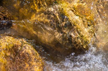 Bir dağ deresinde su. Doğanın ham gücüne ve güzelliğine tanık olun engebeli arazide akan bir su akıntısı gibi, dağlarda amansız bir kararlılıkla yolunu oyuyor.