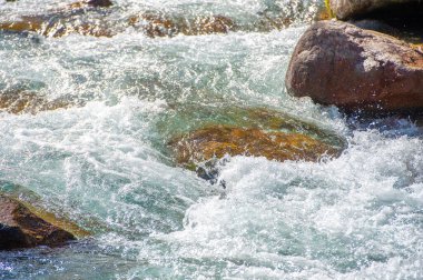 Akan suyun güzelliğini ve doğanın huzurlu manzaralarını yakalayın. Doğadaki ahenk ve sükunete odaklan. Dağınık taşların estetik çekiciliğini vurgula