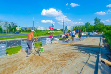 Yaya kaldırımı inşa eden inşaat işçileri, kaldırım yapımında beton ve diğer malzemeler kullanan yaya işçilerine güvenli bir yol sağlayacak
