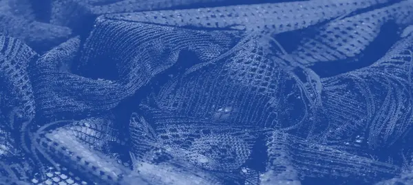 Zarif mavi dantel kumaştan makro bir çekim, ağ benzeri bir doku, yumuşak kıvrımlar ve hafif bir ışıkla aydınlatılmış parıldayan desenler..