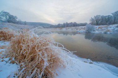 Nefes kesici manzaralı bir kış cenneti. Güneşin doğuşu büyülü bir atmosfer yaratır. Huzurlu ve huzurlu bir atmosfer. Donmuş nehir güzelliği artırır. Doğa en güzel haliyle.