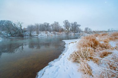 Kış manzarası şaşırtıcı derecede güzel. Altın güneş ışığı huzurlu ve huzurlu bir atmosfer yaratır. Donmuş nehir sükunet ekler..