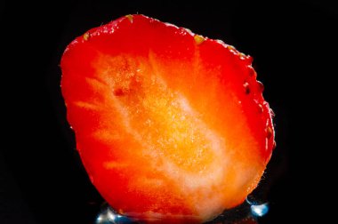 Siyah zemin üzerinde parlak çilek resmi. Yüksek miktarda vitamin içeriği. Sulu ve aromatik meyve seçeneği.