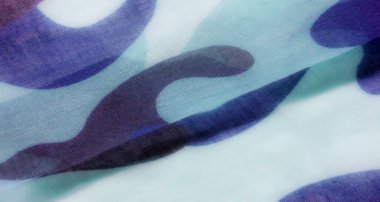 Görüntü, açık mavi, koyu mavi ve su yeşili tonlardan oluşan dalgalı, soyut bir kamuflaj desenine sahip bir kumaşın yakın çekimini gösteriyor..