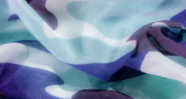 Mavi ve turkuazın tonlarında soyut kamuflaj kumaşı: hassas, organik şekillere sahip geleneksel askeri modellerin akıcı, modern bir yorumu ve görsel derinlik için değişken bir etki