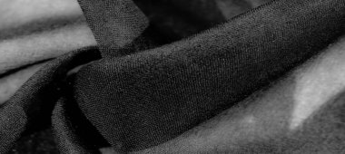 İnce dokuları ve pürüzsüz kıvrımları olan gri pullu bir kumaş, yüzeyinde hafif bir ışık ve gölge oyunu yaratıyor. Yumuşak dokuma derinlik ve incelik katar..